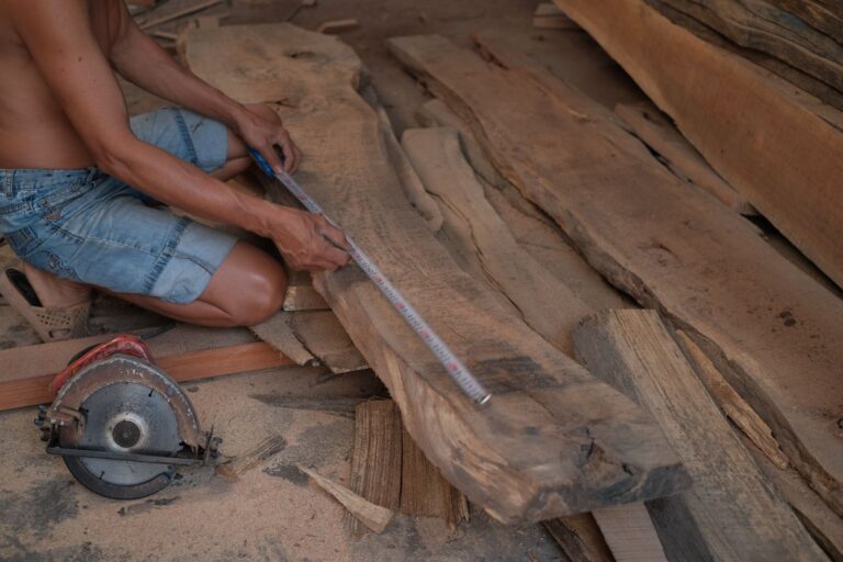 Carpenter measuring a wooden plank with a ruler