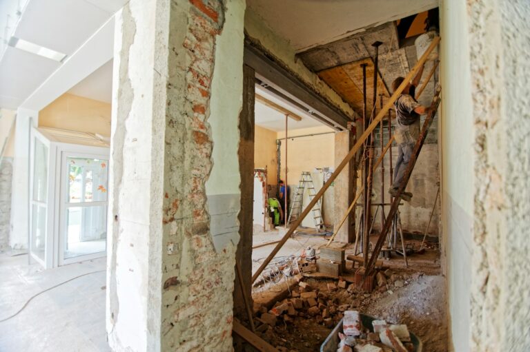 Handyman on a ladder working at the top of an interior wall