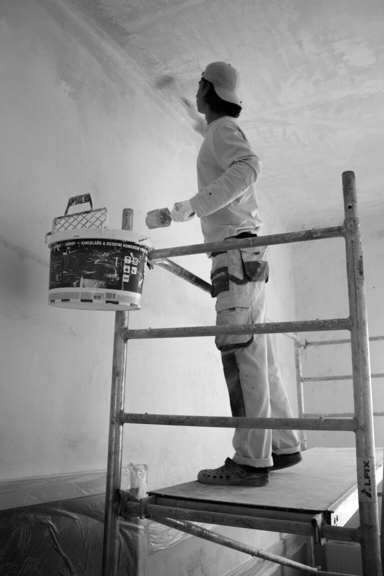Painter using a roller to paint a wall white